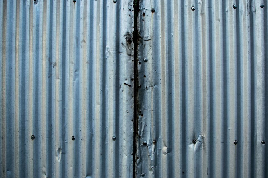 Detailed close-up of a weathered corrugated metal sheet with visible rust and texture.